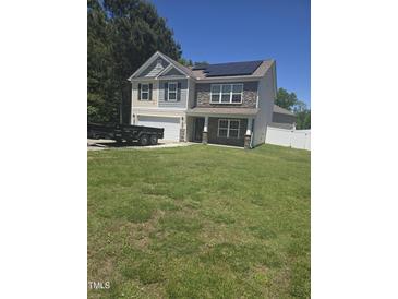 Charming two-story home with a stone facade, solar panels, and a well-manicured lawn on a sunny day at 5016 Gailardia Dr, Zebulon, NC 27597
