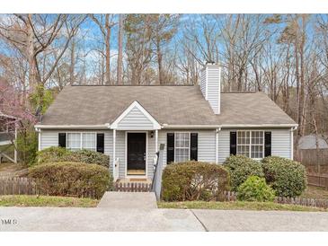 Charming single story home with light gray siding, black shutters, mature landscaping and a welcoming front entrance at 815 Riverbark Ln, Durham, NC 27703