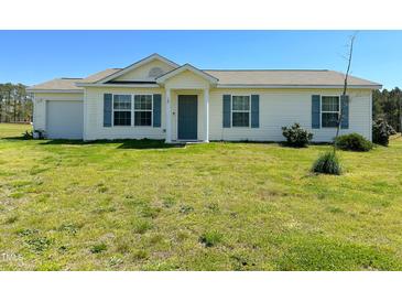 Inviting single-story home with blue shutters, a well-manicured lawn, and an attached garage at 10 Chaney Ln, Louisburg, NC 27549