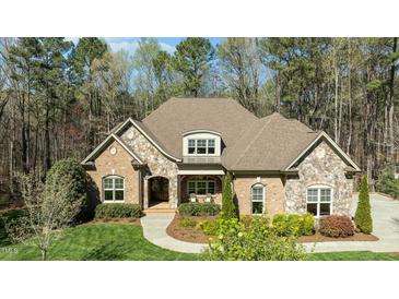 Charming brick and stone home with meticulously landscaped front yard and covered front porch at 1009 High Trail Ct, Wake Forest, NC 27587
