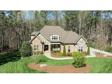 Beautiful brick and stone home with manicured lawn and mature trees at 1009 High Trail Ct, Wake Forest, NC 27587
