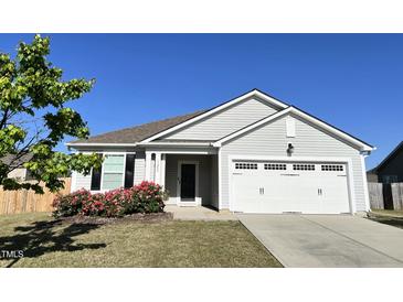Charming single-story home featuring a well-manicured lawn, attached garage, and lovely rose bushes at 1208 Wind Rose Dr, Fuquay Varina, NC 27526