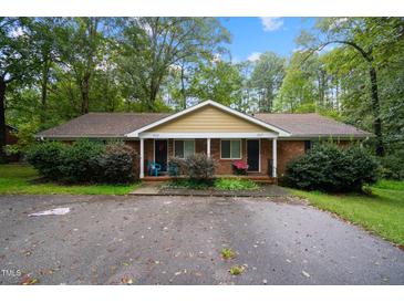 Charming duplex with a brick facade, complemented by a lush, tree-lined front yard at 313 Main St, Knightdale, NC 27545