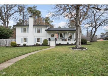 Charming two-story home featuring a brick chimney, a welcoming porch, and well-manicured landscaping at 4900 Skidmore St, Raleigh, NC 27609