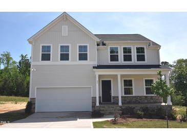 Charming two-story home with stone accents, covered porch, attached garage, and manicured lawn in a suburban setting at 65 Cordoba Dr, Franklinton, NC 27525