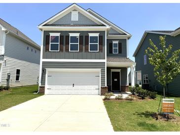 Charming two-story home with a two-car garage, well-maintained landscaping, and a welcoming front porch at 76 Commons Cir, Clayton, NC 27520