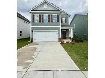 Charming two-story home with a two-car garage and well-maintained front lawn at 76 Commons Cir, Clayton, NC 27520