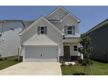 Charming two-story home with a two-car garage, stone accents, and a well-manicured lawn at 84 Commons Cir, Clayton, NC 27520