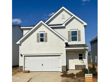 Charming two-story home featuring light siding, a two-car garage, and complemented by stone accents at 84 Commons Cir, Clayton, NC 27520