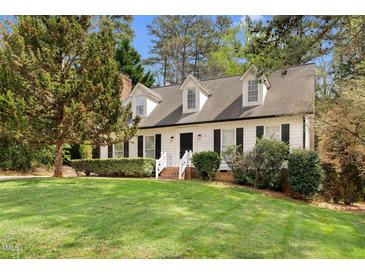 Charming home with white siding, black shutters, dormer windows, brick stairs, and a lush front lawn at 7616 Valley Run Dr, Raleigh, NC 27615
