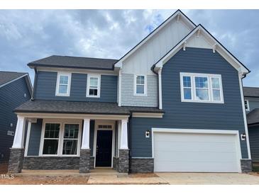 Charming two-story home featuring blue siding, white trim, and a two-car garage at 779 Old Station Pointe, Angier, NC 27501