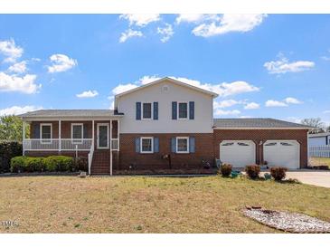 Charming two-story home with a brick facade, a cozy porch, and an attached two-car garage at 153 Glenn Oak Dr, Sanford, NC 27332