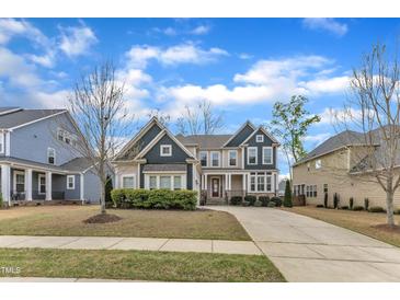 Charming two-story home featuring a well-manicured lawn, a long driveway, and mature landscaping at 215 Mystic Pine Pl, Apex, NC 27539