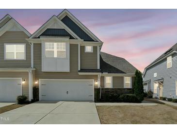 Two-story townhome with a white garage door, stone accents and neat landscaping at 310 Shale Creek Dr, Durham, NC 27703
