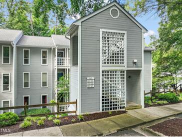 Gray two-story condominium building with landscaped yard, sidewalk, and wooden fence at 4601 Timbermill Ct # 302, Raleigh, NC 27612