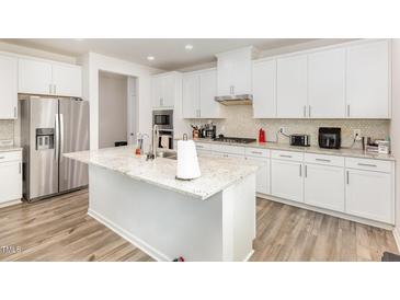 Bright kitchen features a large island with granite countertops and stainless steel appliances at 609 Embrun Run, Wendell, NC 27591