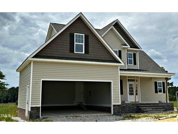 A beige two-story home exhibits a two-car attached garage and black shutters accenting the windows at 85 Prency Ln, Middlesex, NC 27557