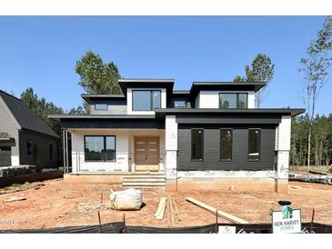 Modern home under construction with a flat roof, double-door entryway, and horizontal siding details at 95 Cherry Bark Dr, Youngsville, NC 27596