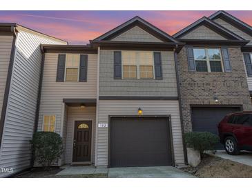 Charming townhome featuring a one-car garage, shutters, and a combination of siding and brick at 102 Bella Pl, Holly Springs, NC 27540
