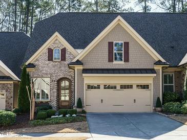 Charming home featuring a brick facade, arched entry, attached garage, and manicured landscaping at 136 Glenpark Pl, Cary, NC 27511