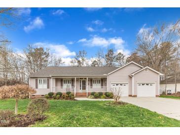 Charming single-story home featuring a well-manicured lawn, inviting front porch, and attached two-car garage at 1410 Briardale Ln, Durham, NC 27712