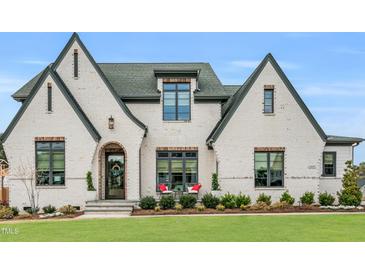 Stunning two-story white brick home with a manicured lawn and a welcoming front entrance with an arched doorway at 1801 Clifton Pines Dr, Cary, NC 27519