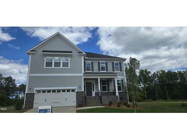 Charming two-story home showcasing stone accents, a two-car garage and manicured lawn under a partly cloudy sky at 20 Bold Dr, Youngsville, NC 27596