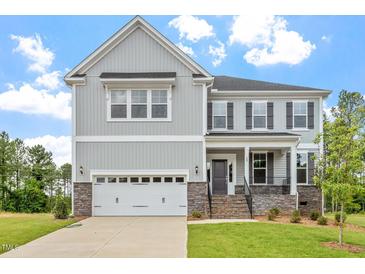 Charming two-story home with stone accents, gray siding, a two-car garage, and a beautifully landscaped front yard at 20 Bold Dr, Youngsville, NC 27596