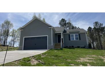 A charming, newly built one-story home with gray siding, a two-car garage, and a well-manicured lawn at 255 Constellation Ct, Benson, NC 27504