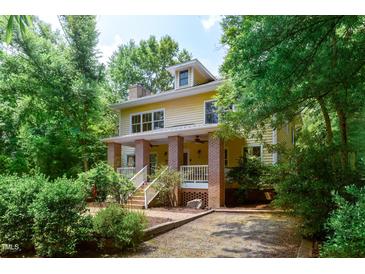 Inviting yellow two-story home boasts a brick porch, lush landscaping, and a welcoming entrance at 407A Hillsborough St, Chapel Hill, NC 27514