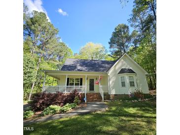 Inviting home with a classic front porch, bay window, and beautifully landscaped yard, all nestled among mature trees at 4116 Tall Pine Dr, Franklinton, NC 27525