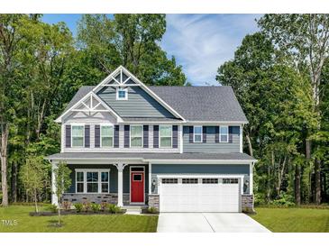 Charming two-story home showcasing a red front door, a two-car garage, and beautiful architectural details at 557 Freedom Trail Dr, Willow Springs, NC 27592