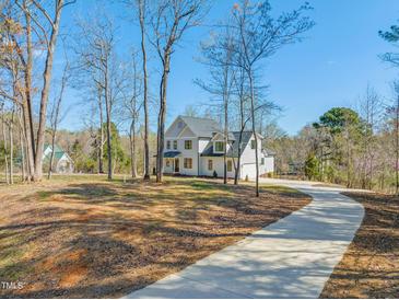 Beautiful two-story home featuring white siding and a long, winding driveway surrounded by lush trees at 7950 Country Knoll Rd, Bahama, NC 27503