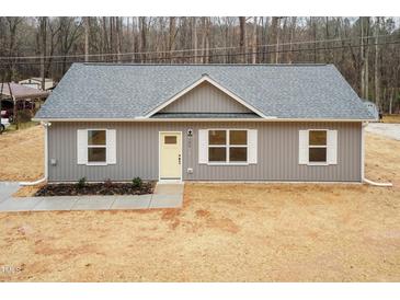 Charming single-story home with gray siding, white trim, and a bright yellow front door at 100 Gates St, Roxboro, NC 27573