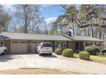 Charming brick home featuring an attached garage, mature trees, and a well-manicured lawn at 105 Elizabeth St, Chapel Hill, NC 27514