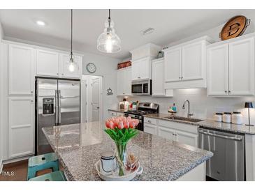 Modern kitchen with stainless steel appliances, granite countertops, and stylish lighting fixtures, and island with tulip display at 109 Shale Creek Dr, Durham, NC 27703