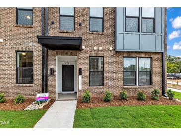 Modern townhome entrance with brick facade, manicured lawn, and visible unit number at 1234 Coach Station Alley # 101, Raleigh, NC 27601