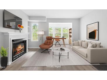 Bright living room featuring a fireplace, large windows, and space for a home office setup at 1300 Hillbrow Ln # 204, Raleigh, NC 27615
