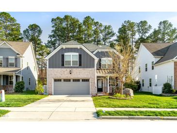 Charming two-story home with a brick and gray exterior, a well-manicured lawn, and an attached two-car garage at 1301 Elliott Ridge Ln, Morrisville, NC 27560