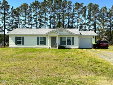 Charming one-story home with a well-maintained lawn and attached garage, nestled among tall trees at 20 Golden Poppy Ln, Youngsville, NC 27596