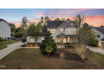Stunning two-story home featuring manicured lawns and mature trees at sunset at 240 Swann Trl, Clayton, NC 27527