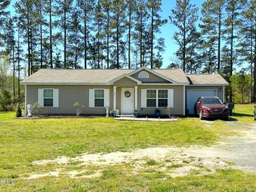 Charming single-story home featuring a manicured lawn, white shutters, and a welcoming front porch at 30 Golden Poppy Ln, Youngsville, NC 27596