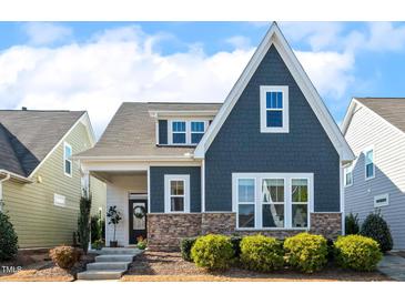 Charming two-story home featuring stone accents and a well-manicured front yard with green shrubbery at 405 Daisy Grove Ln, Holly Springs, NC 27540
