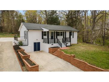 Beautifully renovated exterior of home featuring a brick retaining wall and covered front porch at 4509 Alamance Baptist Church Loop, Burlington, NC 27215