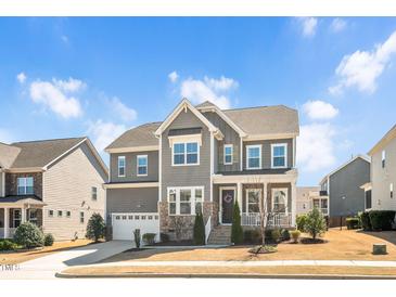 Charming gray two-story home with stone accents, covered porch, manicured lawn and attached two-car garage at 715 White Oak Pond Rd, Apex, NC 27523