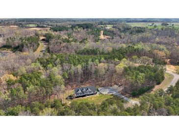 Stunning aerial view of modern home nestled in a lush, wooded landscape with driveway and ample parking at 90 Ferncrest Ct, Roxboro, NC 27574