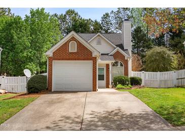 Charming brick and vinyl home featuring an attached garage, manicured lawn and mature trees at 200 Adefield Ln, Holly Springs, NC 27540