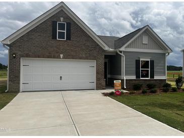 Charming single-story home featuring a two-car garage, brick and siding accents, and a well-manicured front yard at 34 E American Marigold Dr # 64, Benson, NC 27504