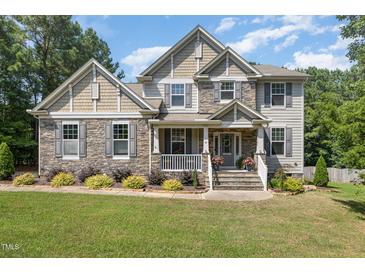 Charming two-story home showcasing a stone and shingle facade, complemented by a well-manicured lawn and mature trees at 45 Pebble Creek Dr, Franklinton, NC 27525