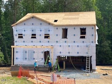 New two-story home featuring pre-construction with building materials and exposed beams in a wooded area at 62 Atherton Circle, Angier, NC 27501